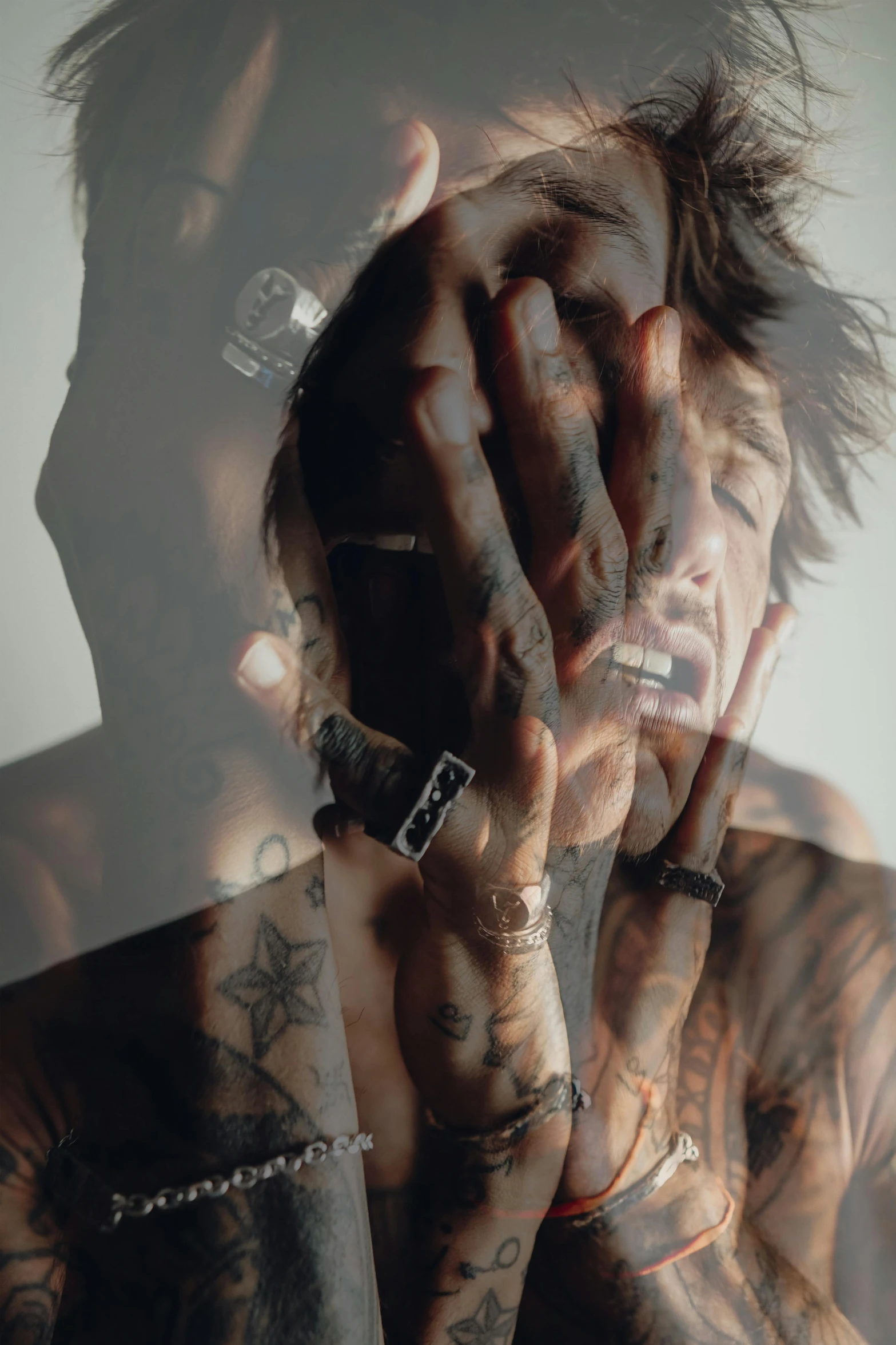 a man with his hand on his face and tattoos on