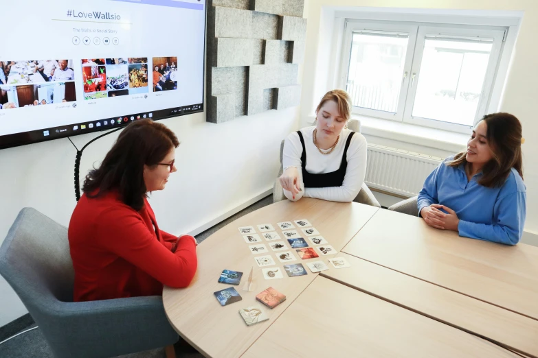 three people sitting at a table playing a game