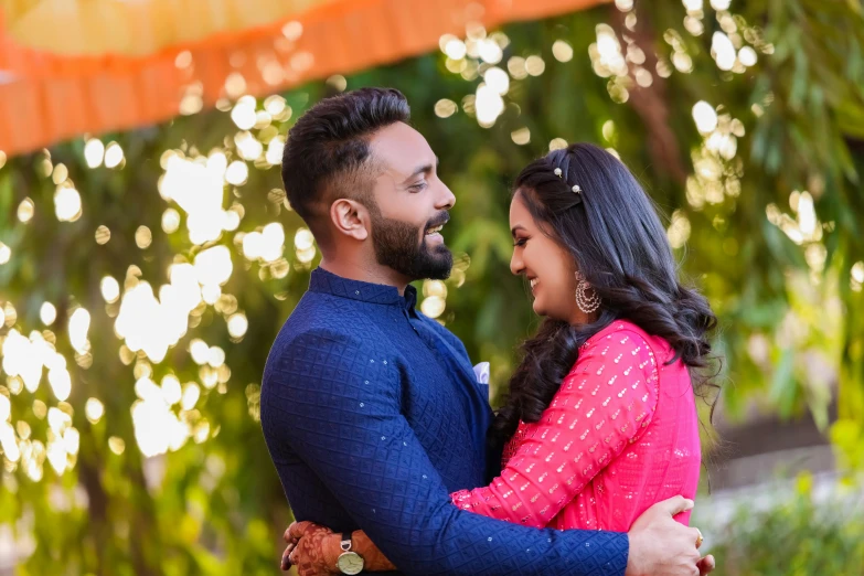 an indian couple cuddles under a lit tree