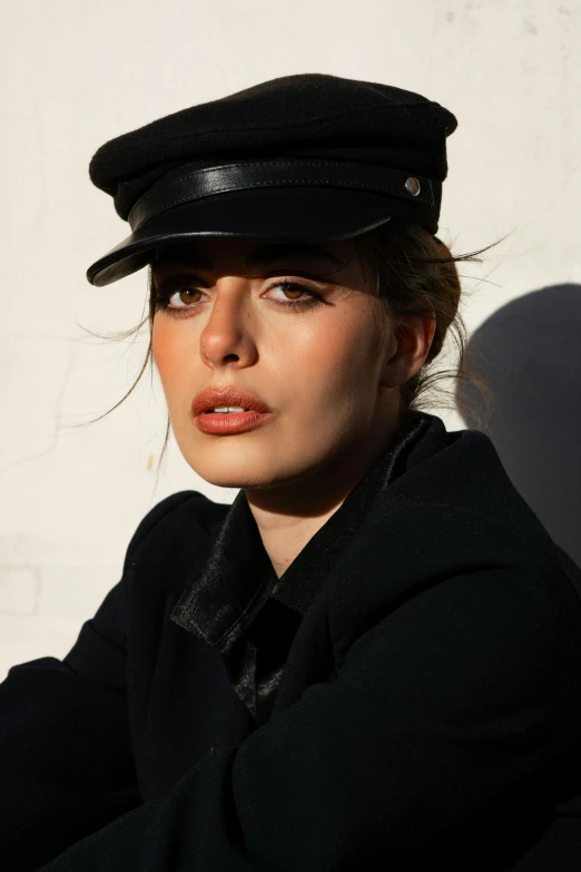 a woman wearing a hat in front of a wall