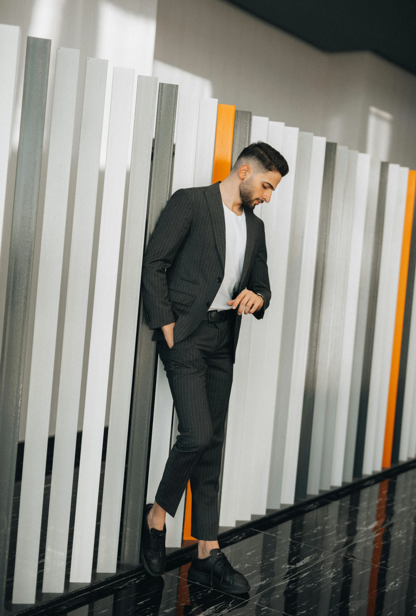 a man with dark suit, white t - shirt and black shoes walking