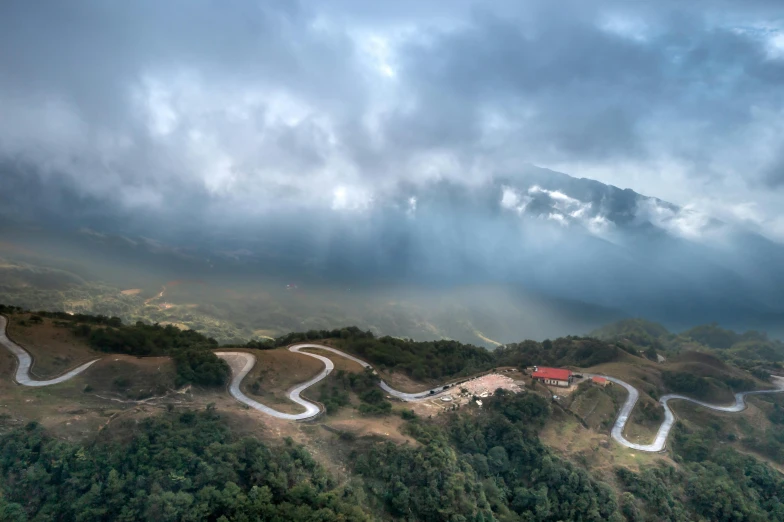 an aerial view of a road winding in to trees