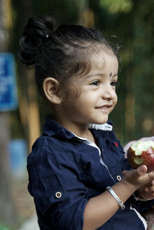 little girl showing off a green and white apple