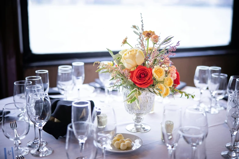 a vase of flowers on a table with wine glasses and napkins