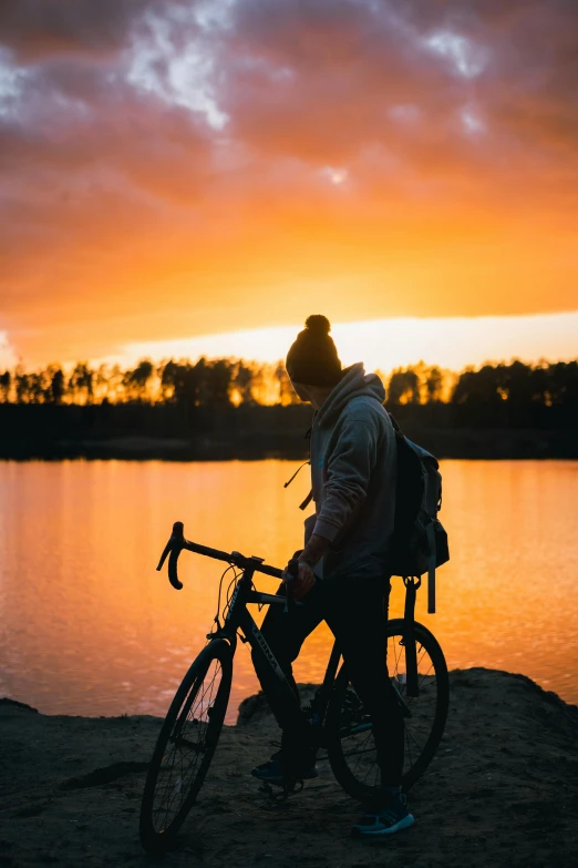 a person standing next to a bike near water