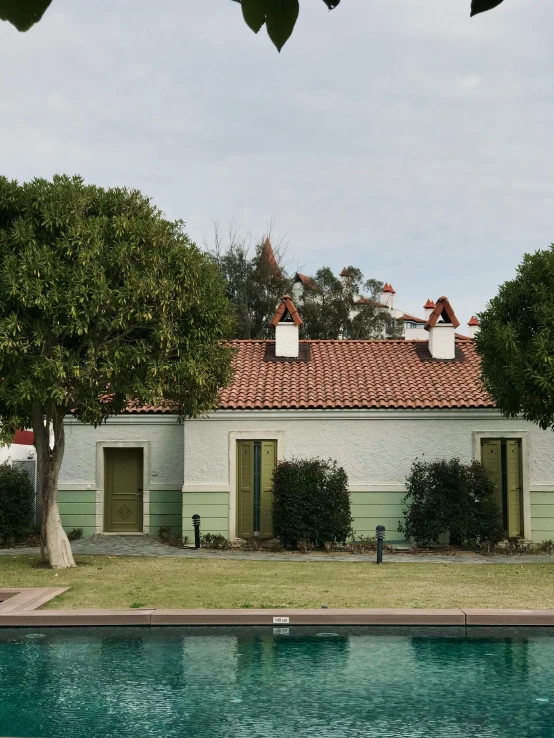 a green house with two dormer windows on the side