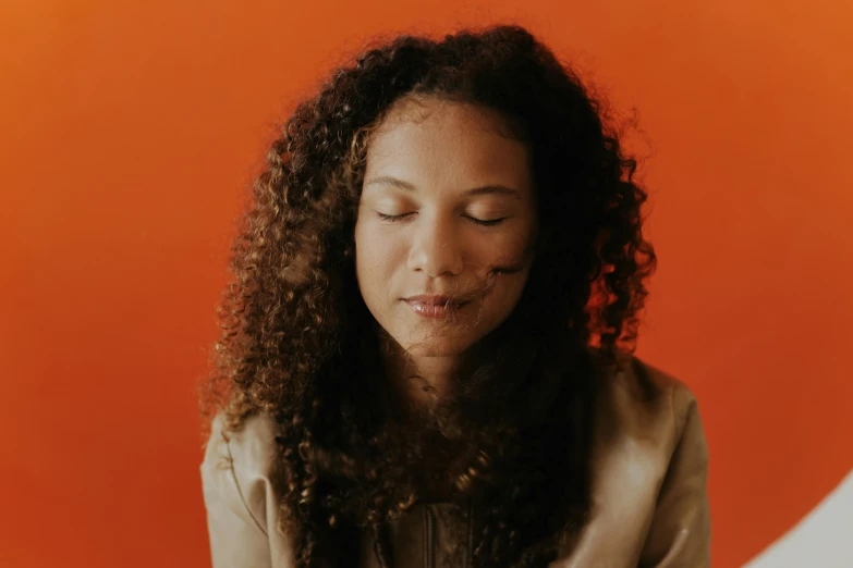 a young woman with long curly hair is smiling and looking down