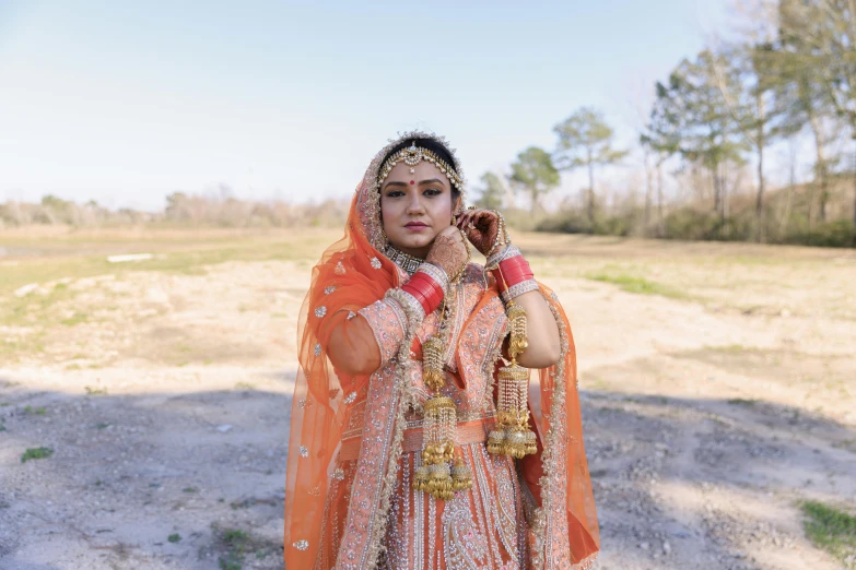 a woman standing in a field while wearing a bridal suit