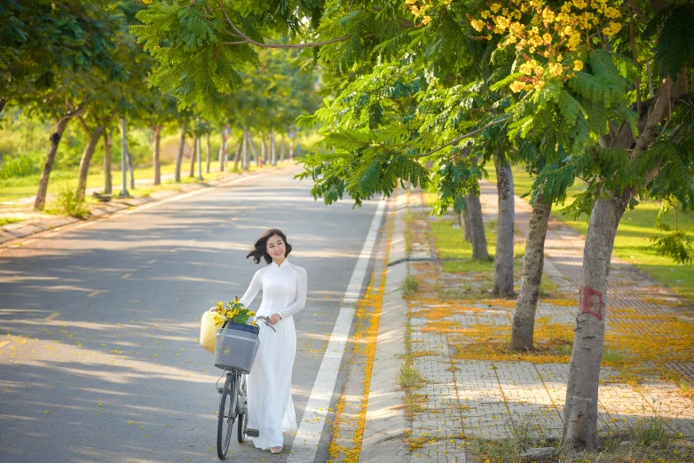 a woman is holding a bicycle while wearing a dress