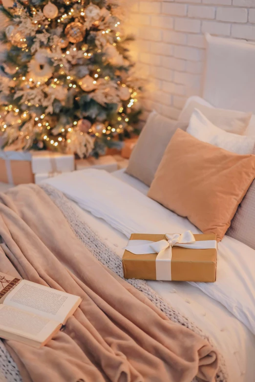 a bed with pillows, blankets and a holiday tree in the background