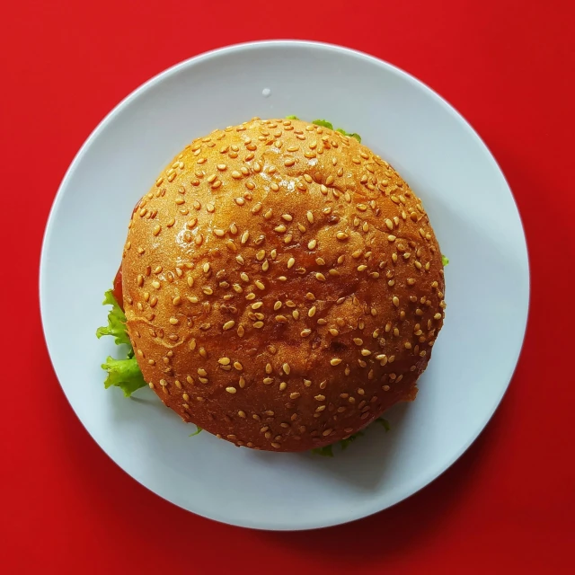 a hamburger on a plate on a red table