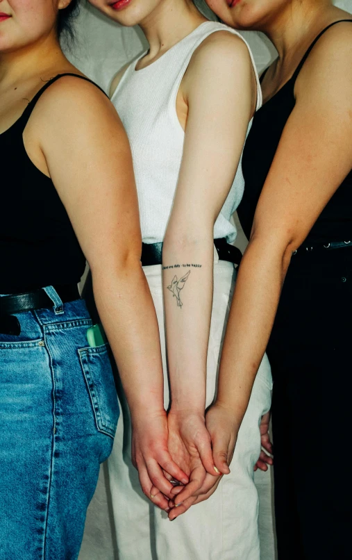 three women standing next to each other holding hands