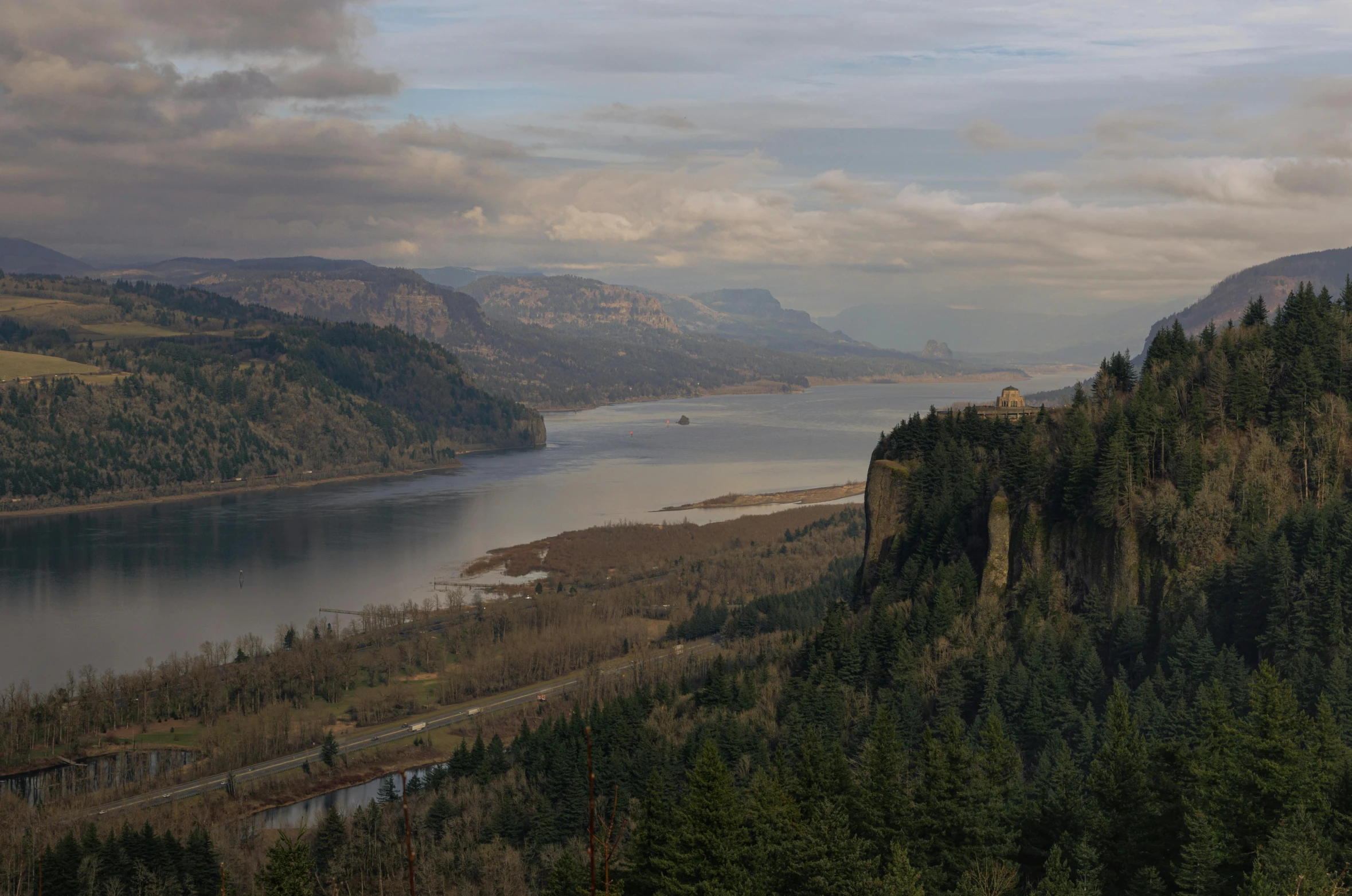 the large river has a mountain side with trees