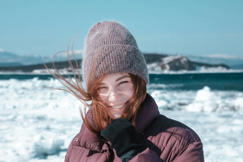 the young woman smiles as she stands in front of a body of water