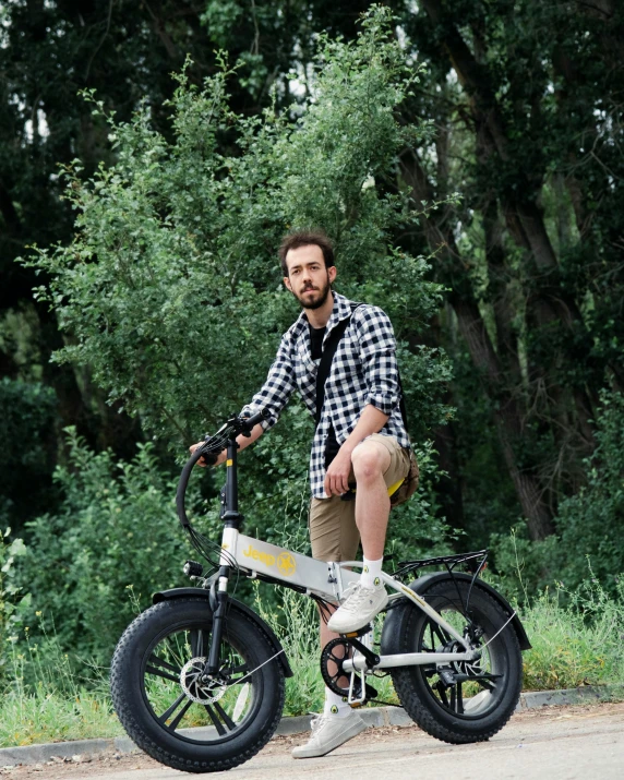 a man in plaid shirt riding an old time style bicycle