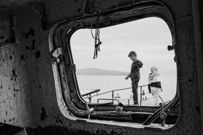 a boat mirror is reflecting people standing by the ship's bow