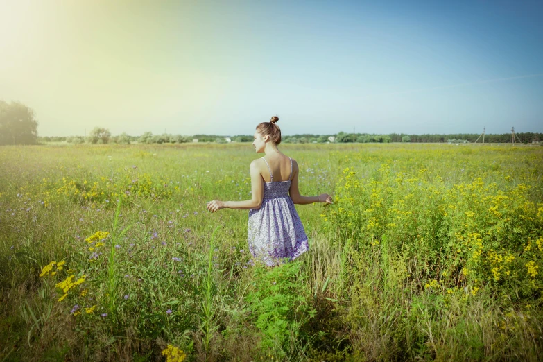 a beautiful young woman standing in a field with tall grass