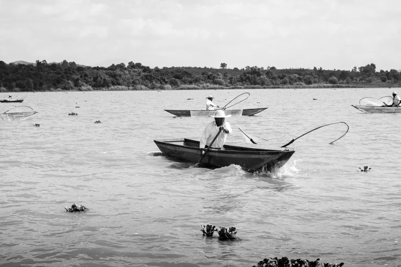 a man standing on top of a boat holding a fish in it's mouth