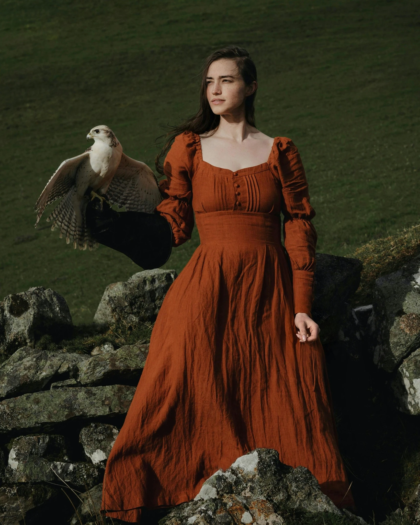 woman in brown dress posing with a bird on her arm