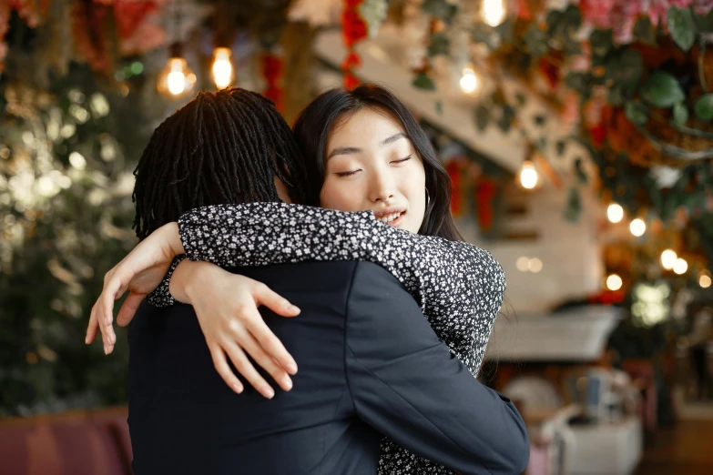 the young couple is hugging while walking through a christmas tree