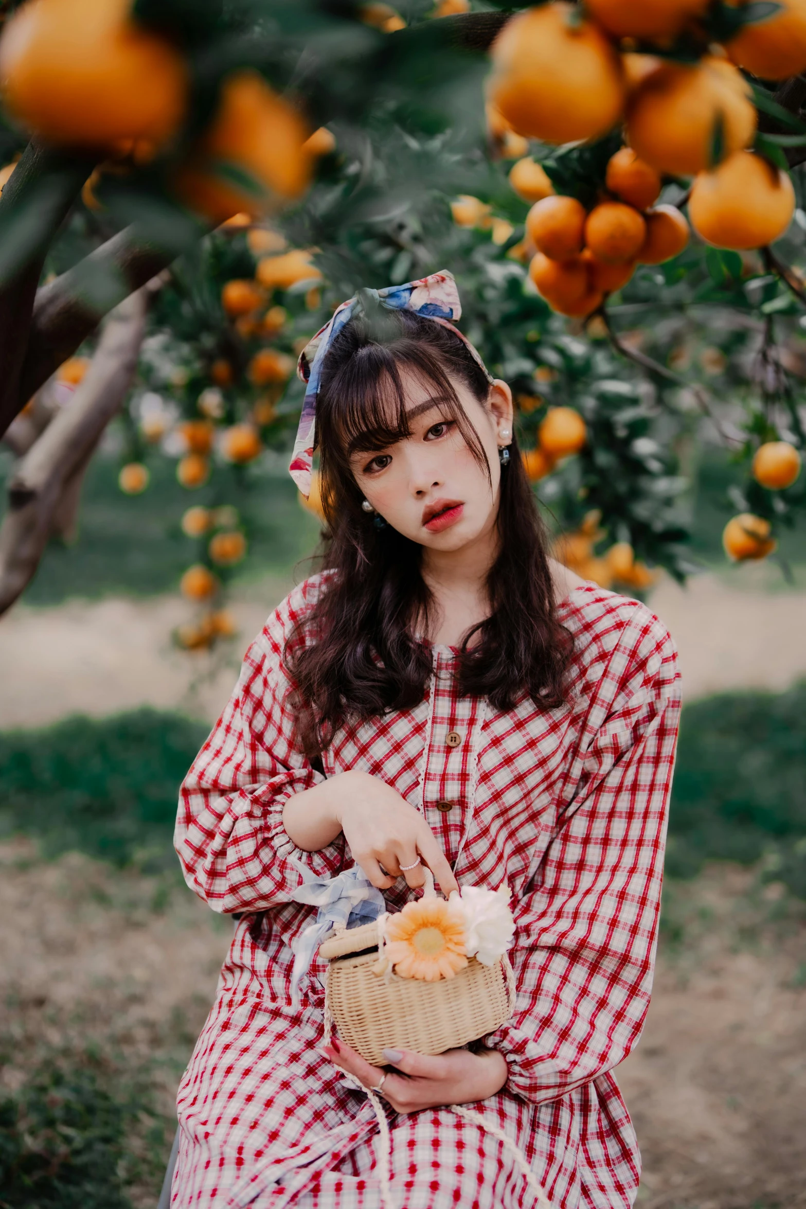 little girl with hat holding basket of food sitting under orange tree
