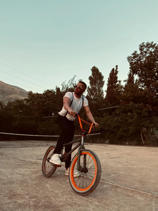 a man riding an orange bicycle across a parking lot