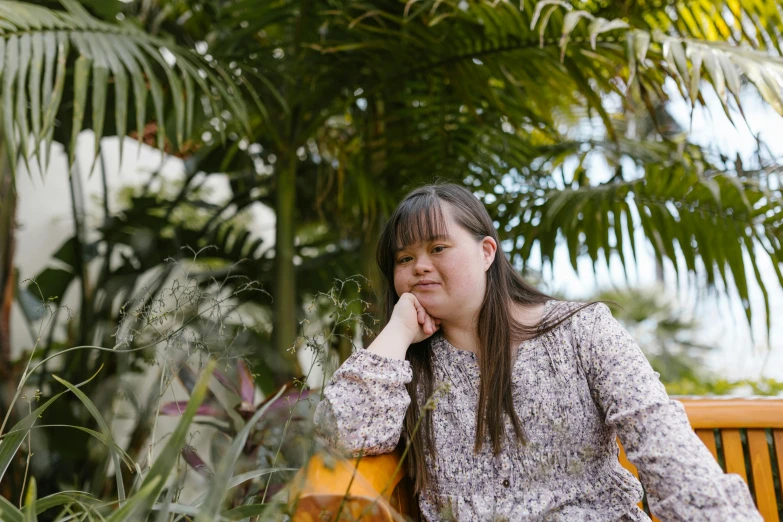 a woman is sitting on a bench by some trees