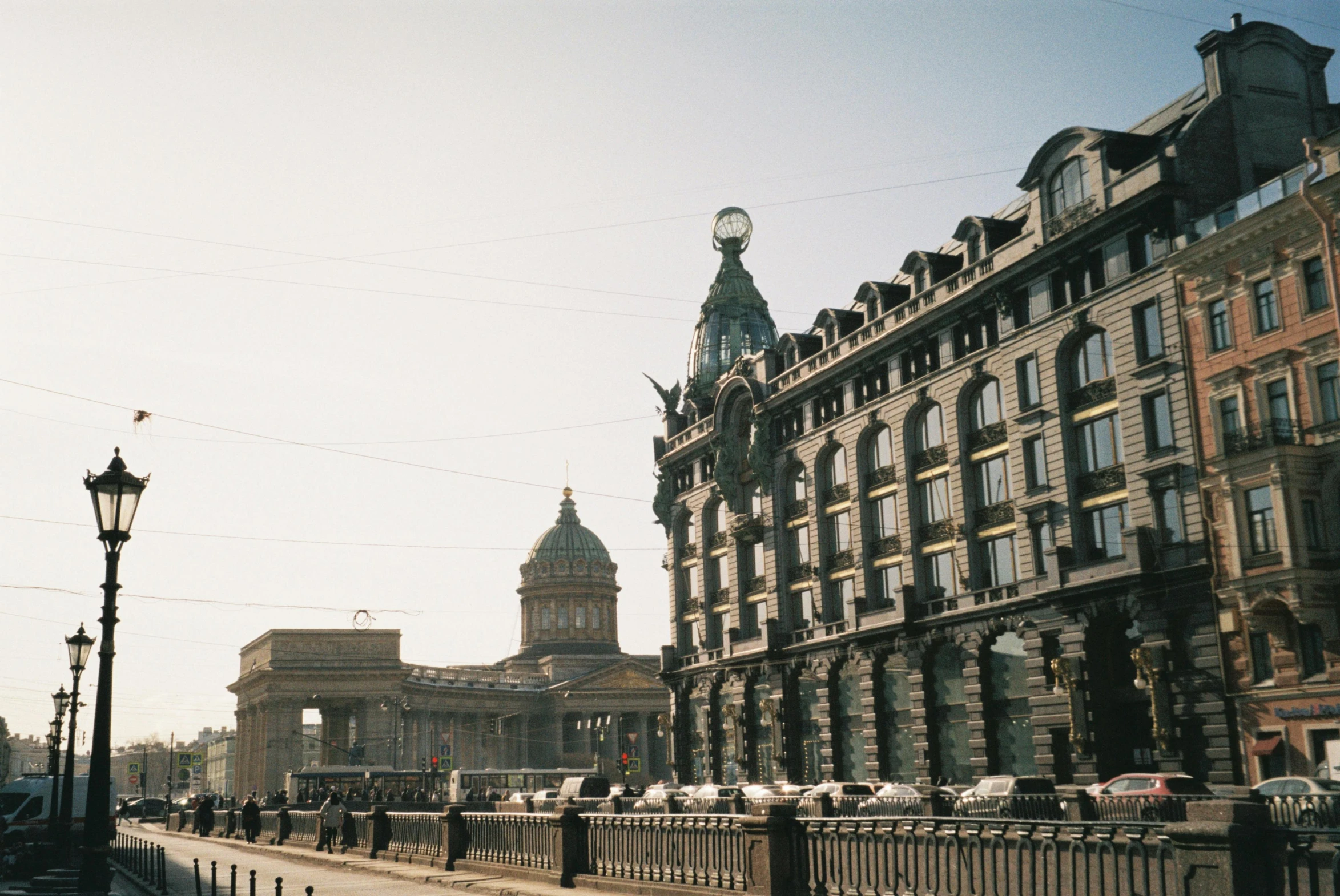 people walk on a street next to a row of buildings