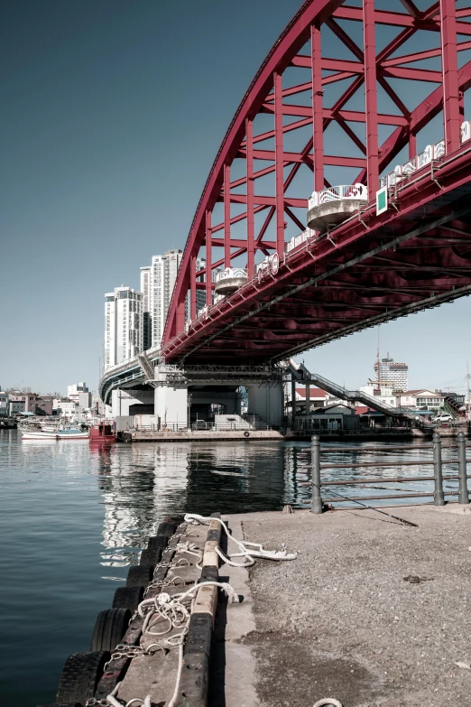 a red bridge spanning over water with buildings in the background