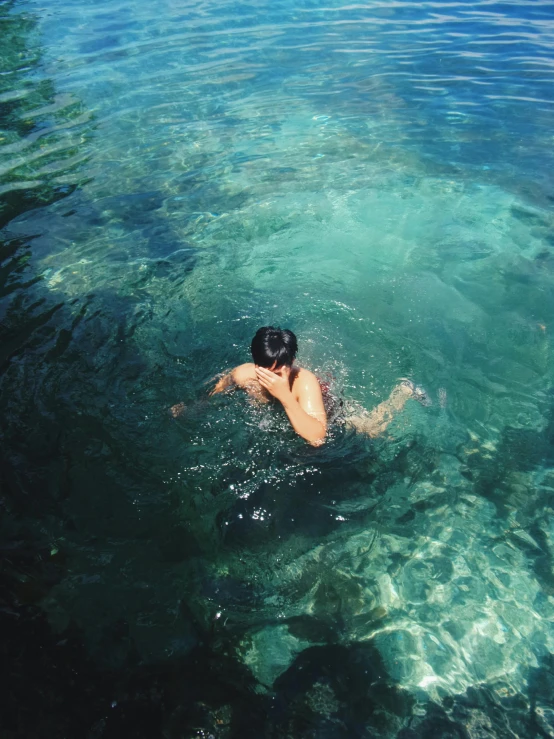 a man swimming in a lagoon near the shore