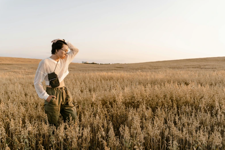 a woman stands in an open field with her arms around her head