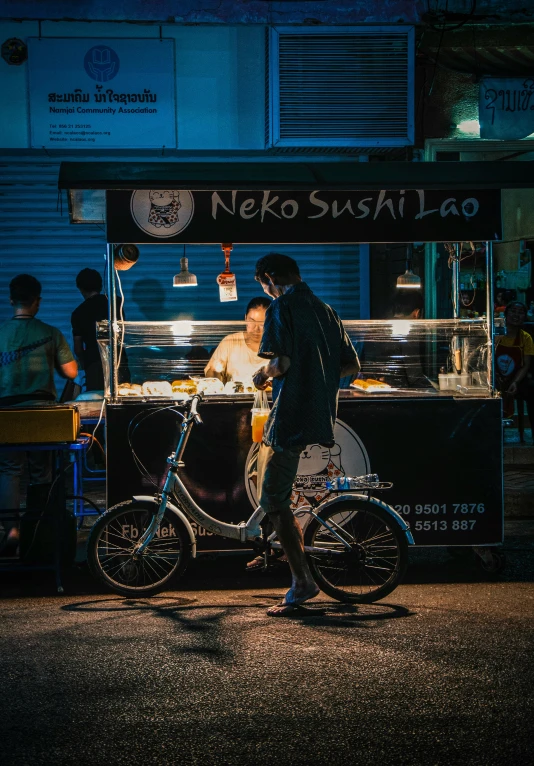 a man walks past a food cart at night