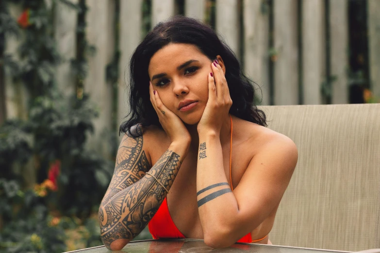 a girl with tattooed arm and body, posing at a table