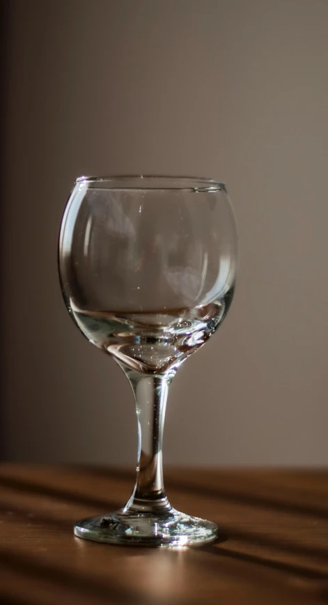 an empty glass on a table in a dimly lit room