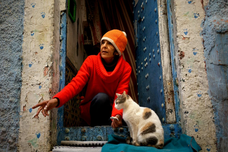 an old woman looking out a window with a cat sitting beside her