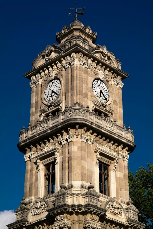 the tower is made of stone with a cross and two clocks on each side