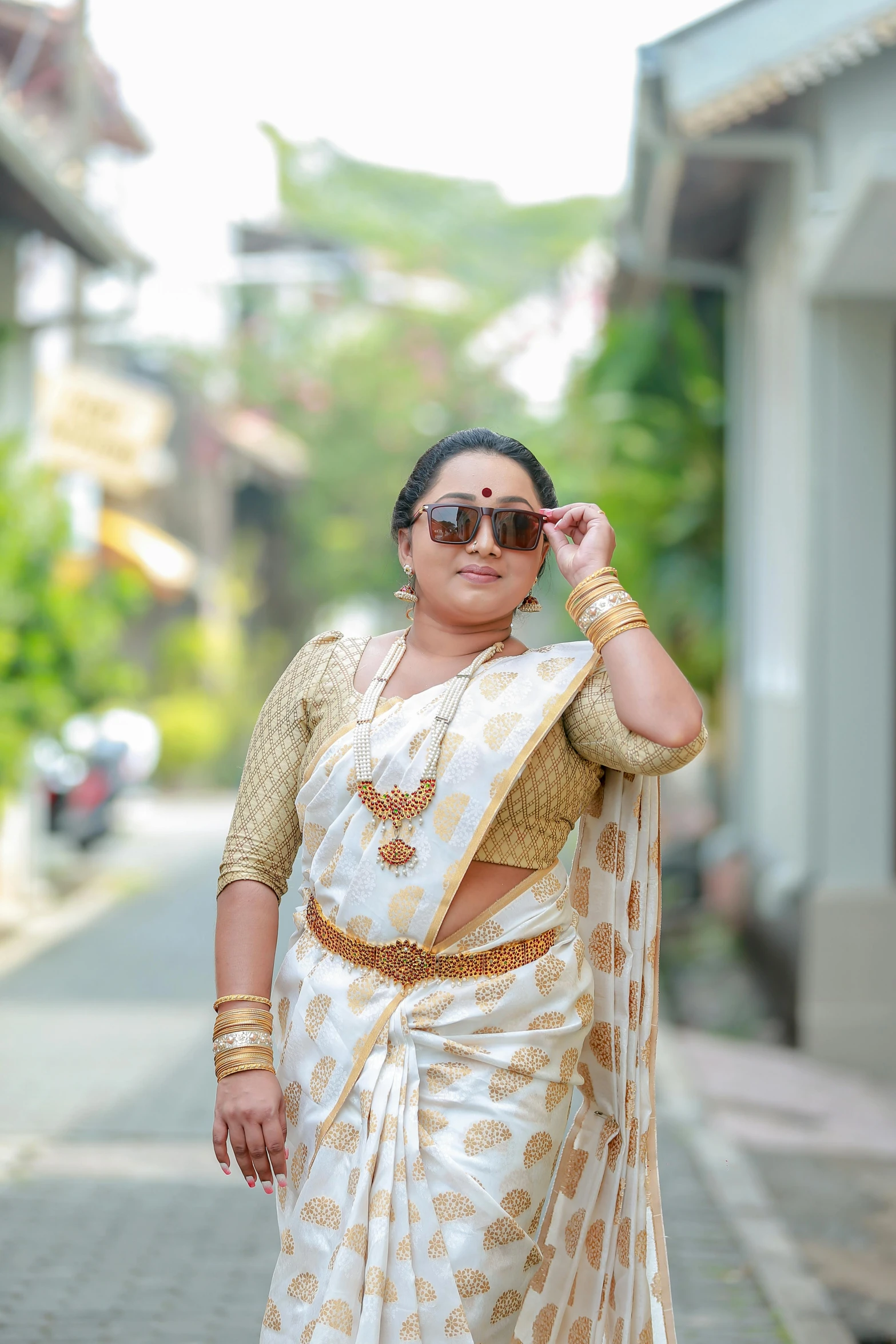 woman in white sari standing on street with her hand to her forehead