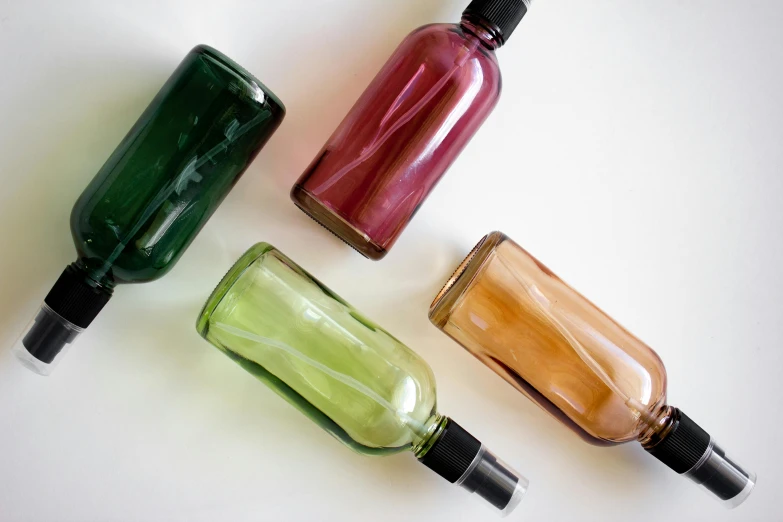 three glass bottles with a red one and two green bottles next to each other