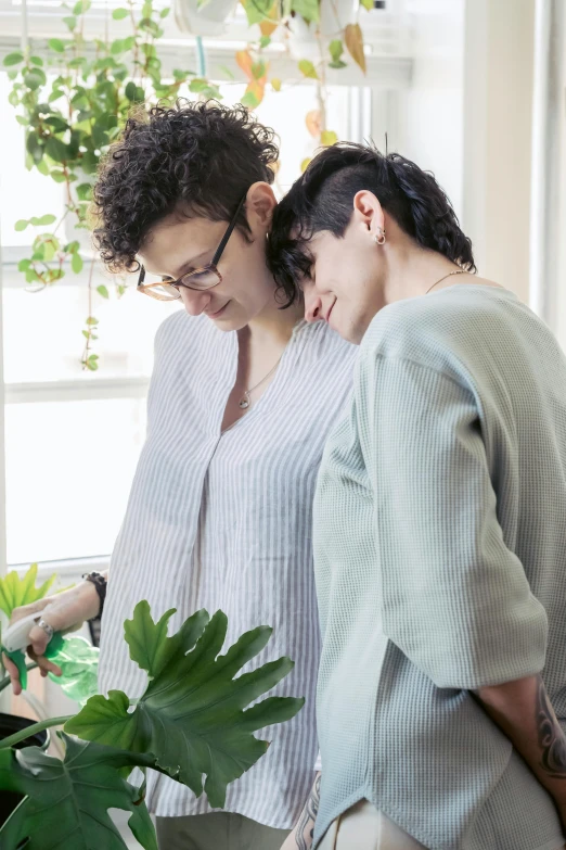 two women standing next to each other  green plants