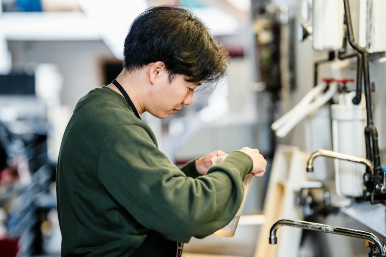 an asian man fixing a sink in a factory