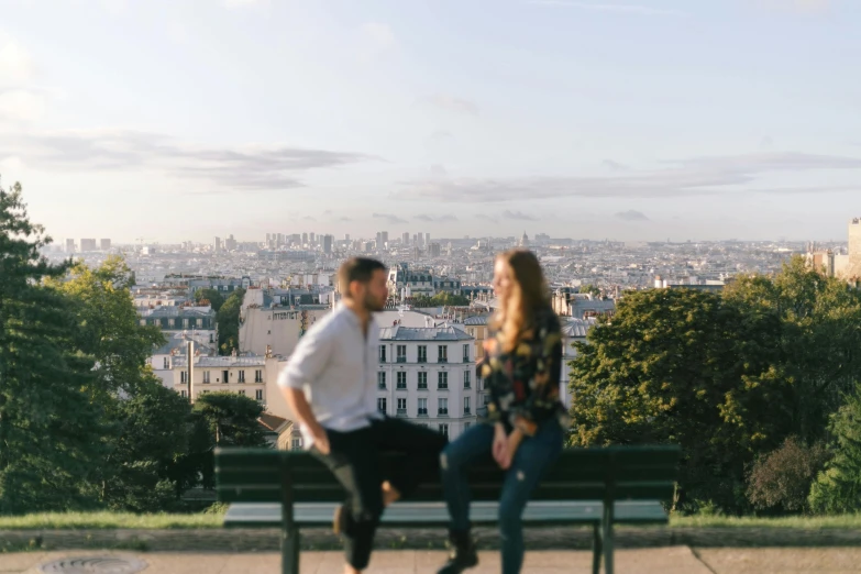 two people sit on a bench overlooking the city