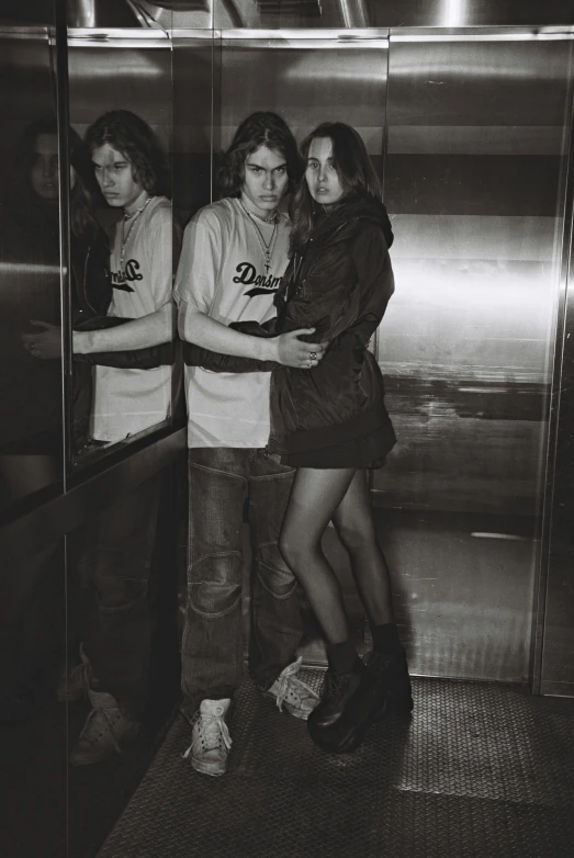 three women standing near an elevator in black and white