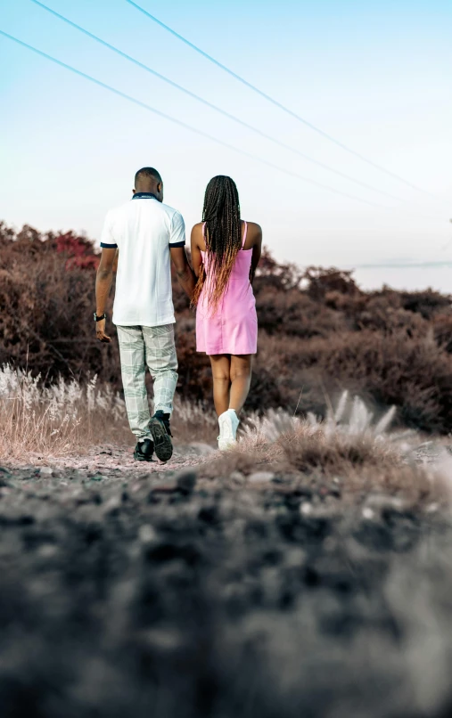 two people are walking in the grass holding hands