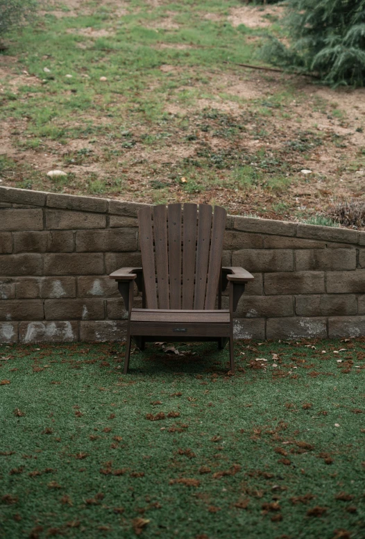 a lawn chair sits in front of a brick wall