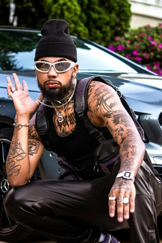 a tattooed man with sunglasses sitting on the curb