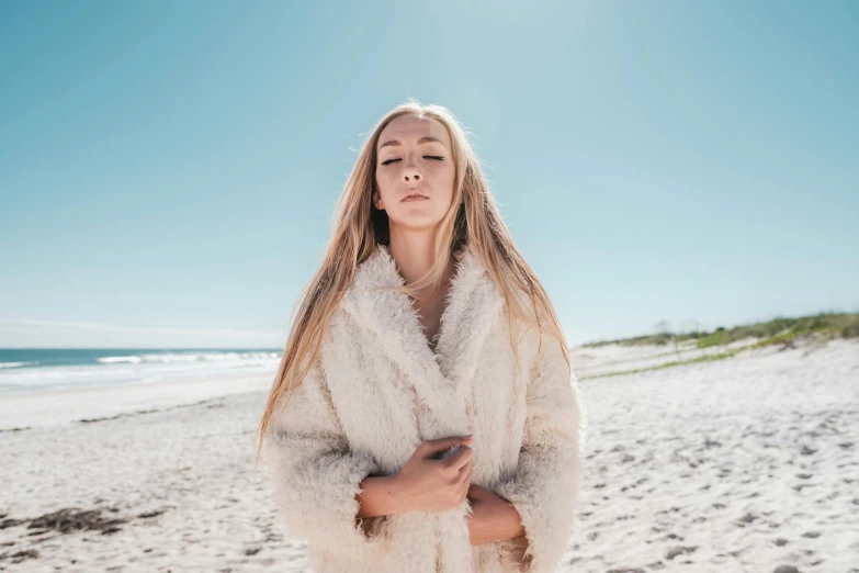 a woman with long blonde hair is standing on the beach