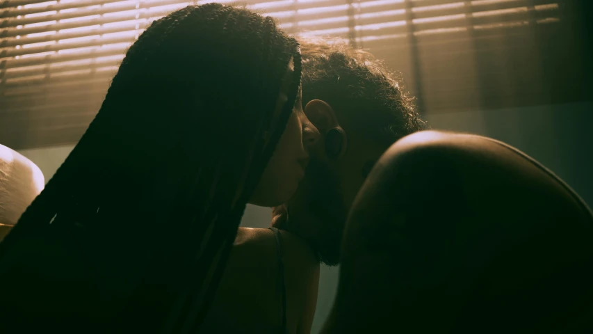 a man and woman are sitting in front of a window with the blinds closed