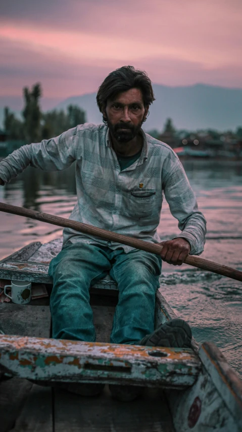 a man sits in the water on his boat with a stick