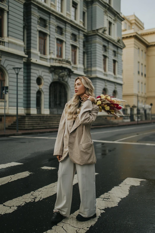 the young woman in the long coat is holding flowers