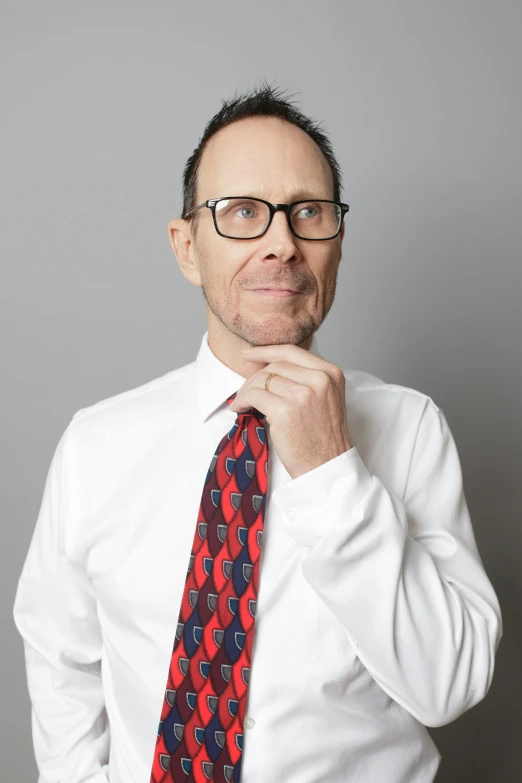 a man wearing glasses and a tie posing for a po